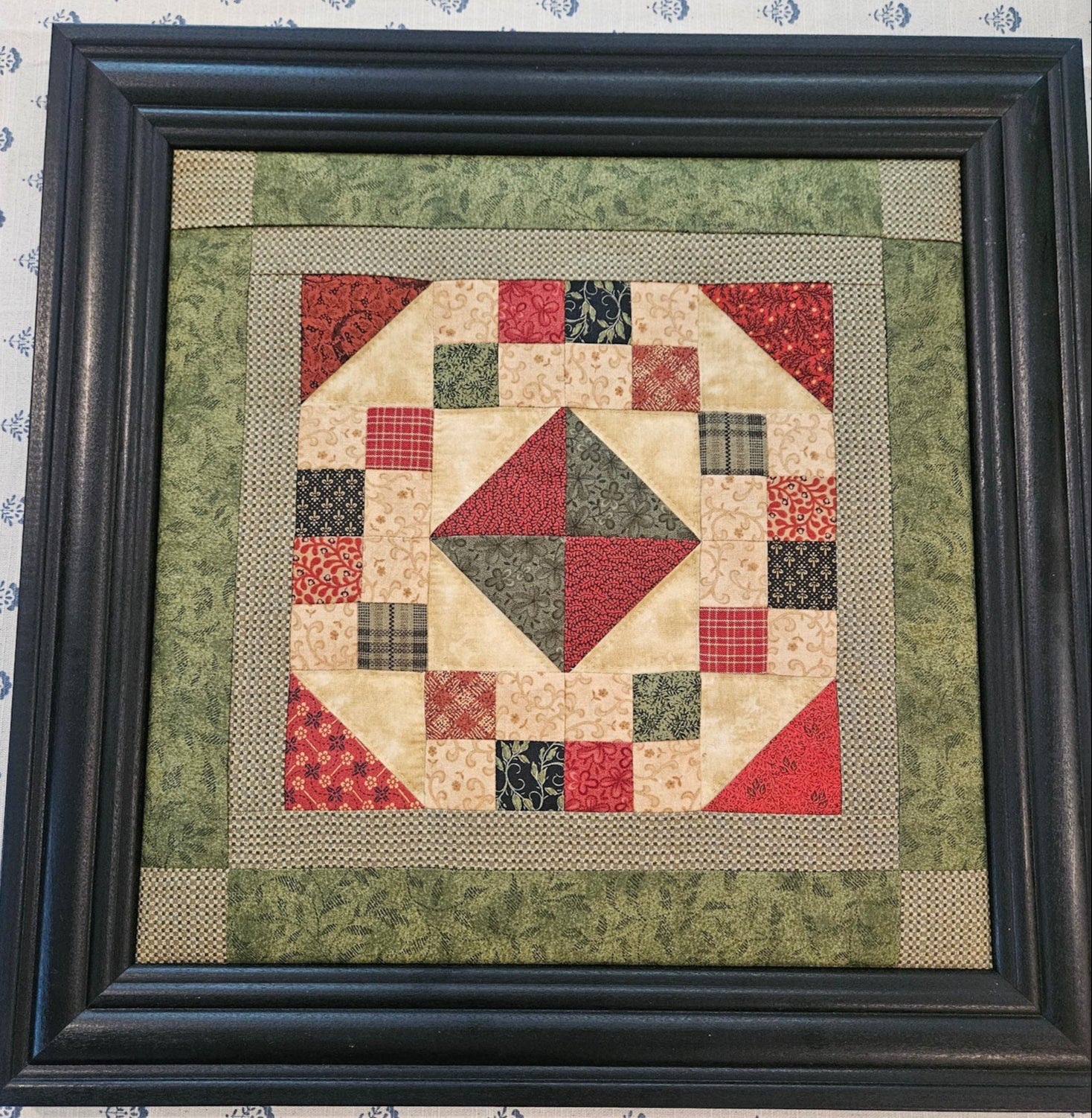 Framed patchwork quilt with geometric pattern on a textured surface