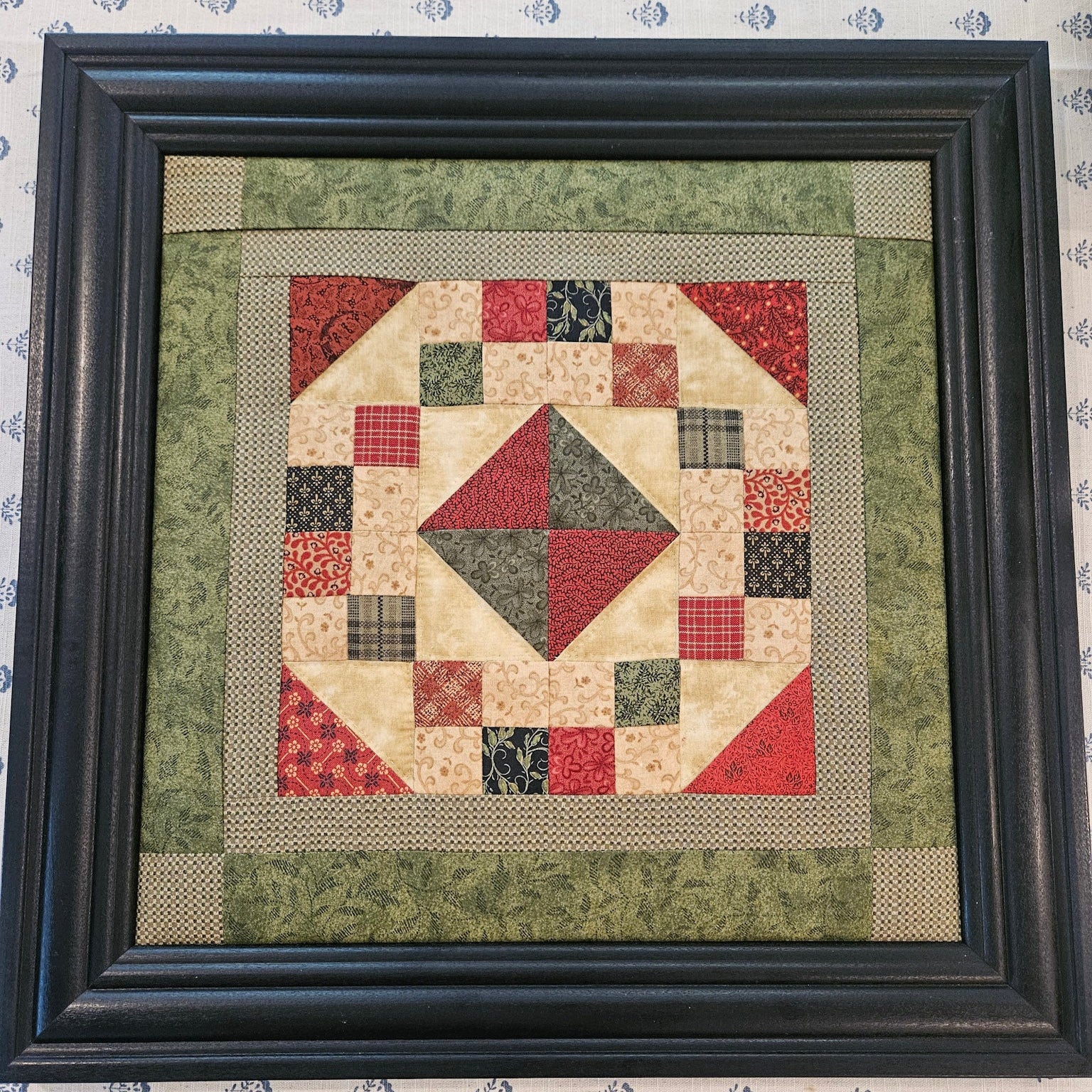 Framed patchwork quilt with geometric pattern on a textured surface